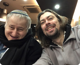 Two men happily pose for a selfie, smiling and capturing a joyful moment together.