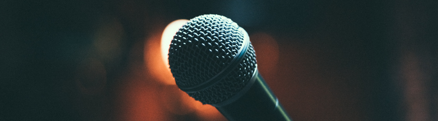 A close up of a microphone in front of a blurred background.